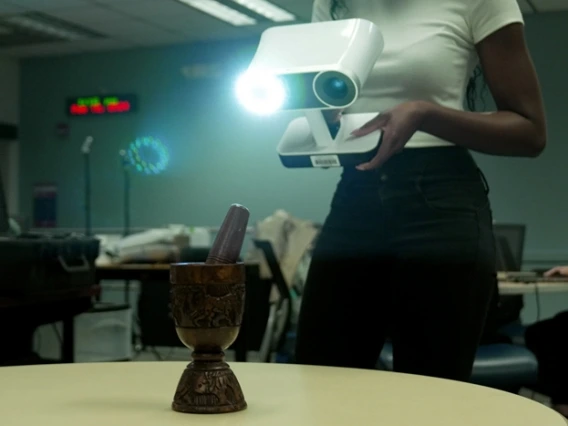 a person holding a lidar scanner with a camera lens and light scanning an mortar and pestle sitting on a table