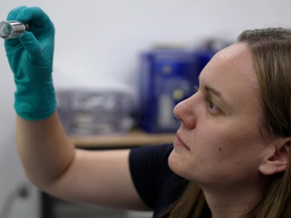 Jessica Barnes looking at a vial containing Bennu asteroid sample